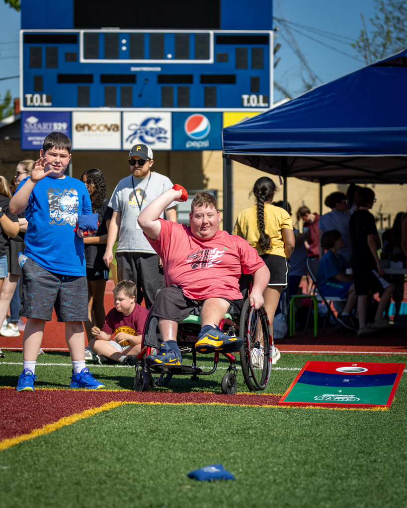a student throwing a red bag during a game of corn hole at the exceptional spring games. 
