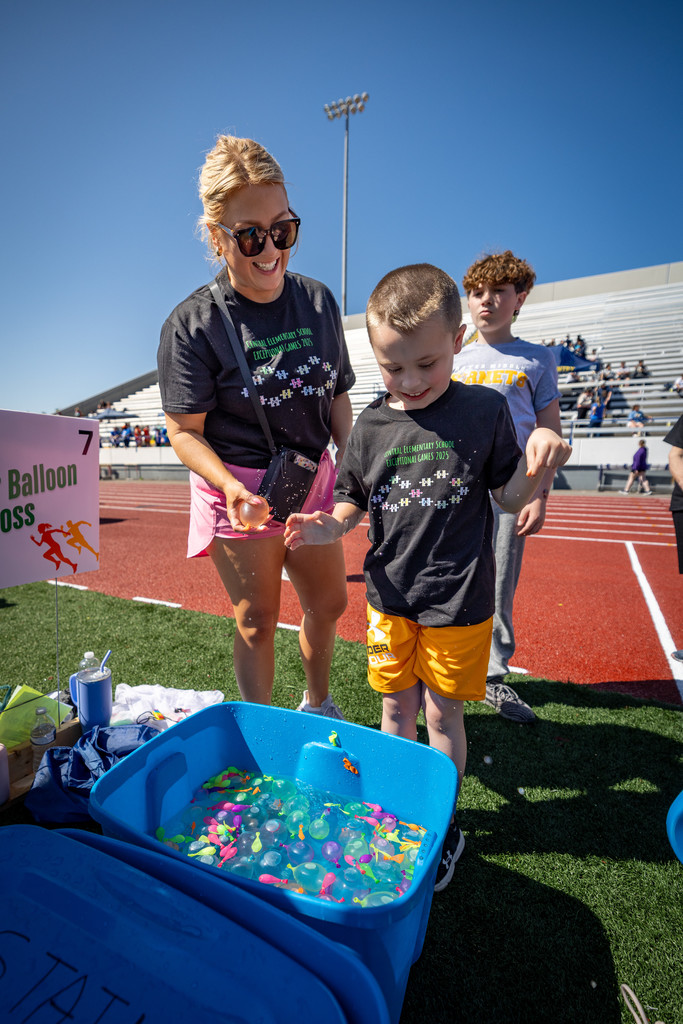 a student and volunteer picking out water balloons for the water balloon toss.