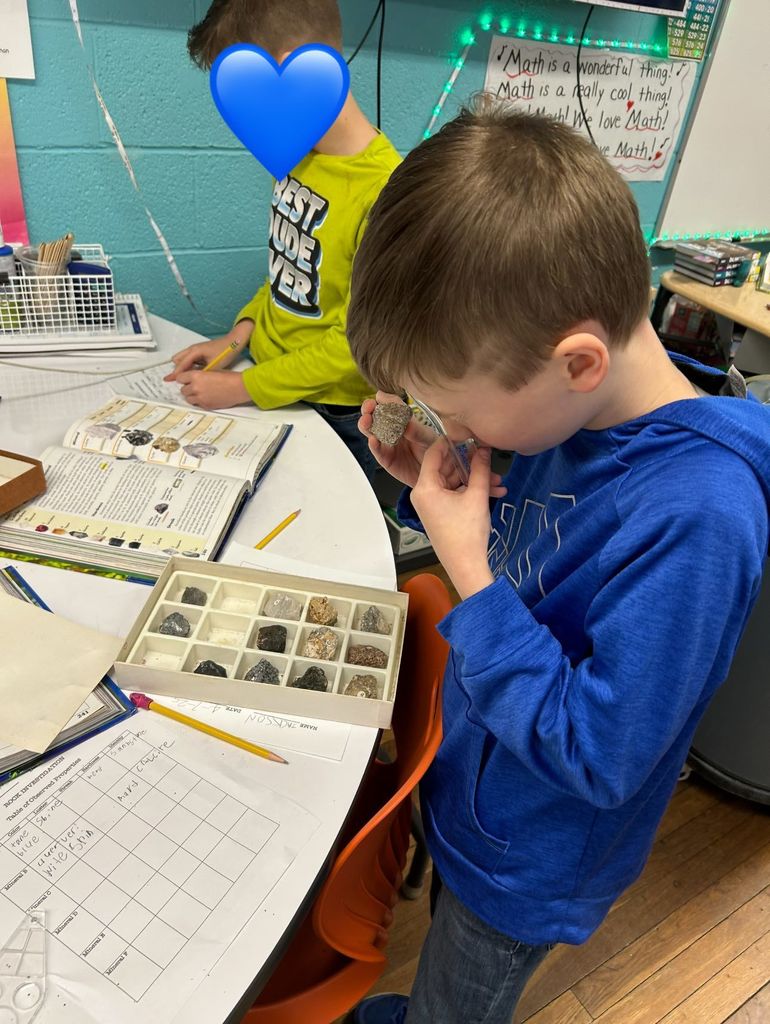 student looking at a mineral through a magnifying glass.