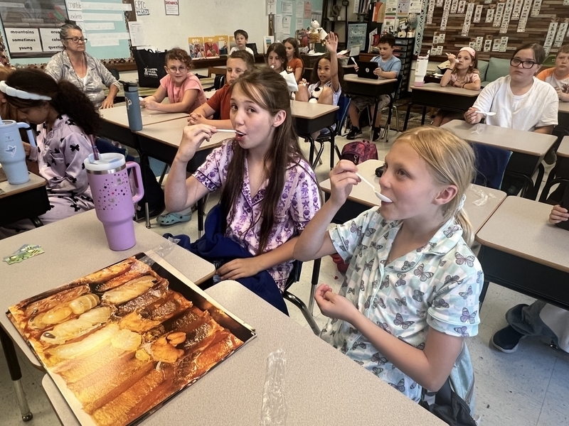 two students at belle elementary tasting honey.