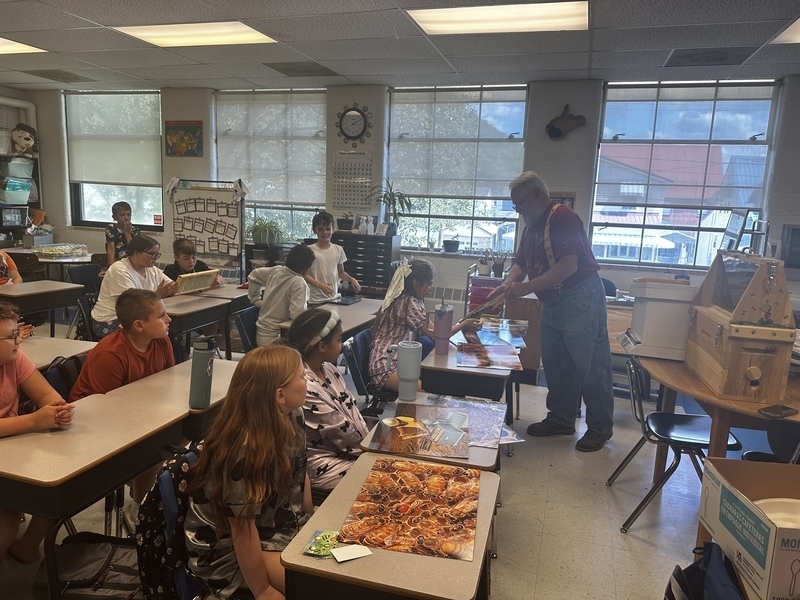a local beekeeper showing belle students a honeycomb from one of his hives.