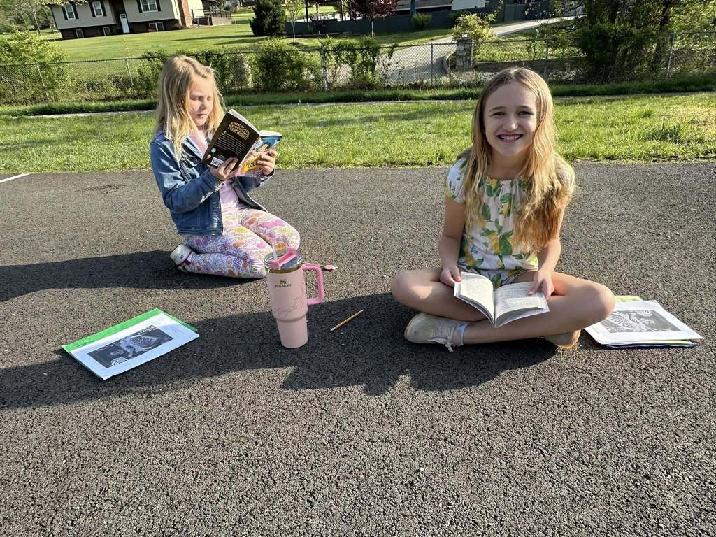 two students at alum creek elementary reading their book together.