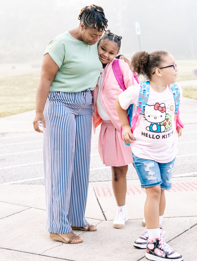student hugging her principal before walking into school on the first day.
