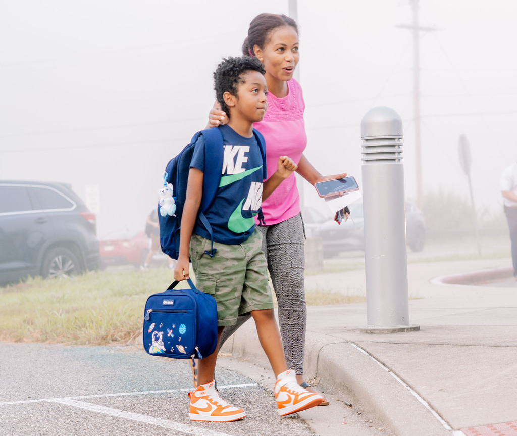 a woman walking her son into school on the first day.