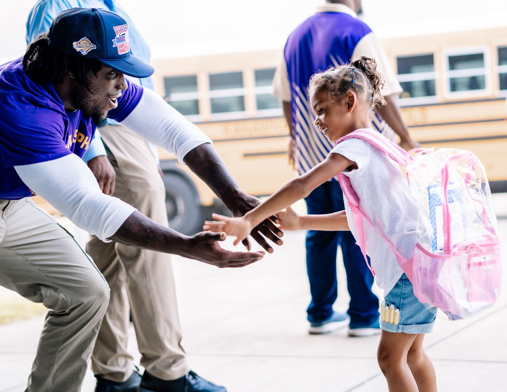 young giving a high five to a teacher as she walking into school.