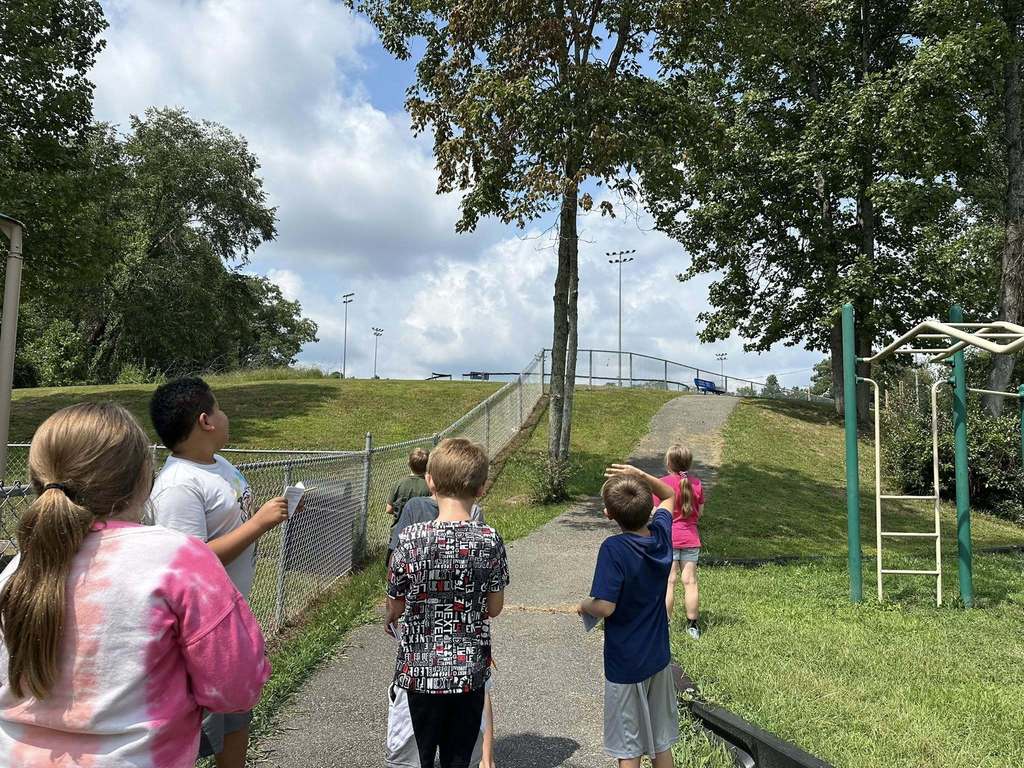 students at alum creek looking at the clouds in the sky as part of their science lesson.