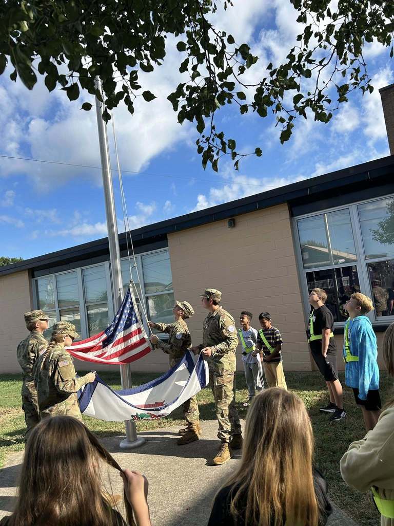 nhs rotc students showing nes students how to raise and lower the american flag.