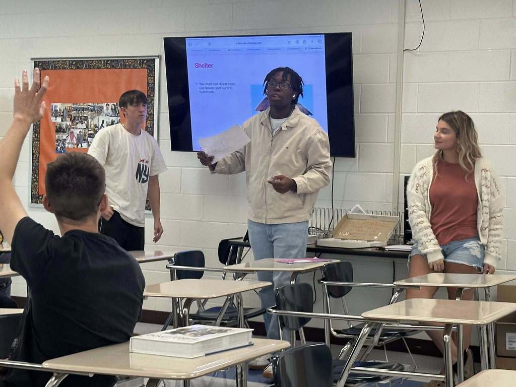 three capital high school students showing the rights and laws of the island country they created for a civics lesson.