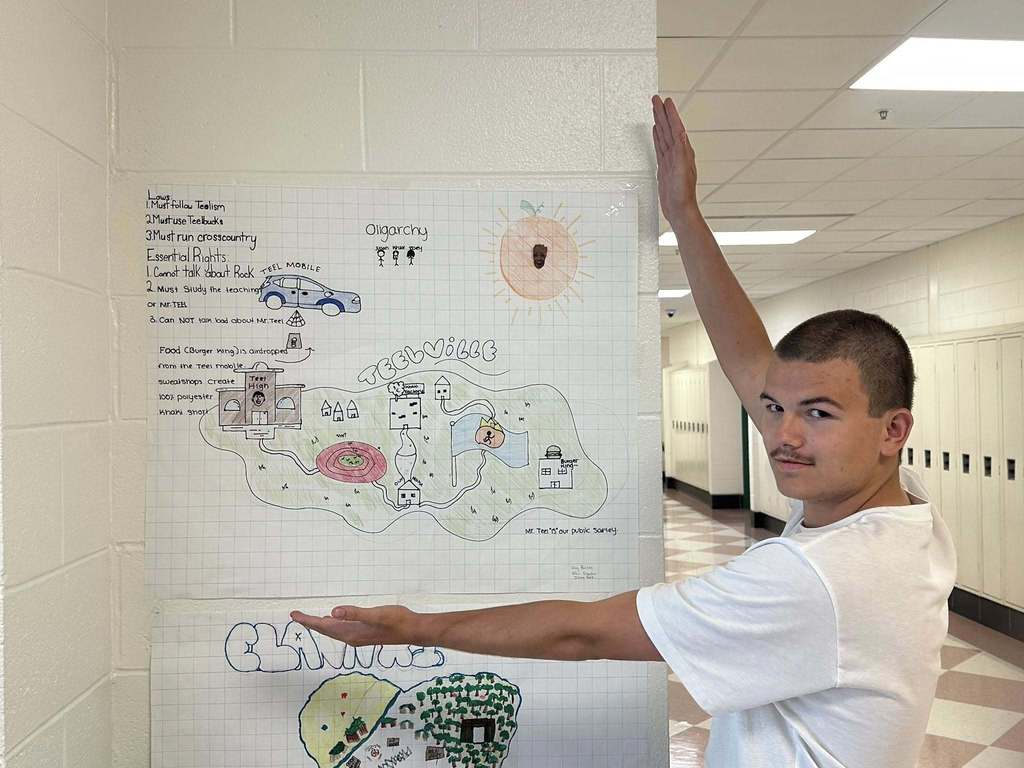 student showing the rules and regulations for the new island country his group created during a civics lesson.