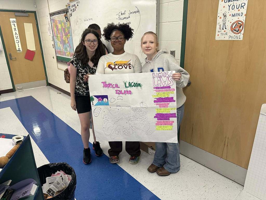 three capital high school students showing the rights and laws of the island country they created for a civics lesson.