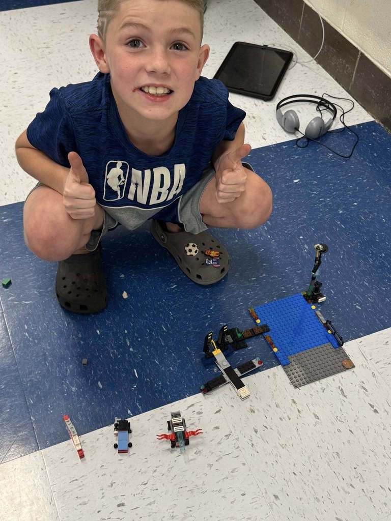 a student posing with his lego cars. 