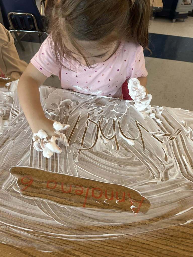 bridgeview elementary student writing her name in shaving cream during a handwriting lesson.