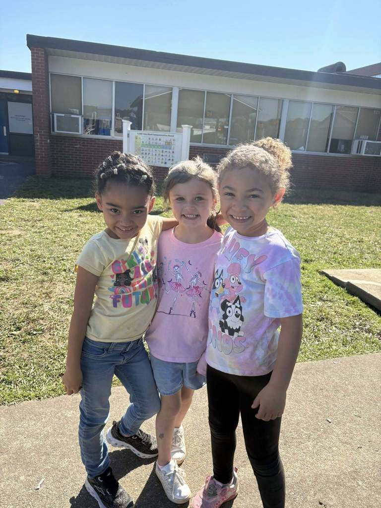 three kindergarten students at bridgeview elementary posing for a picture on the playground.