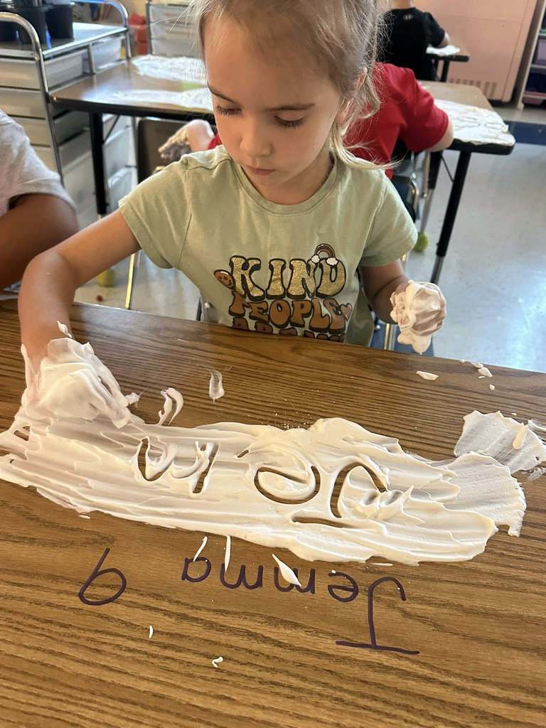 bridgeview elementary student writing her name in shaving cream during a handwriting lesson.