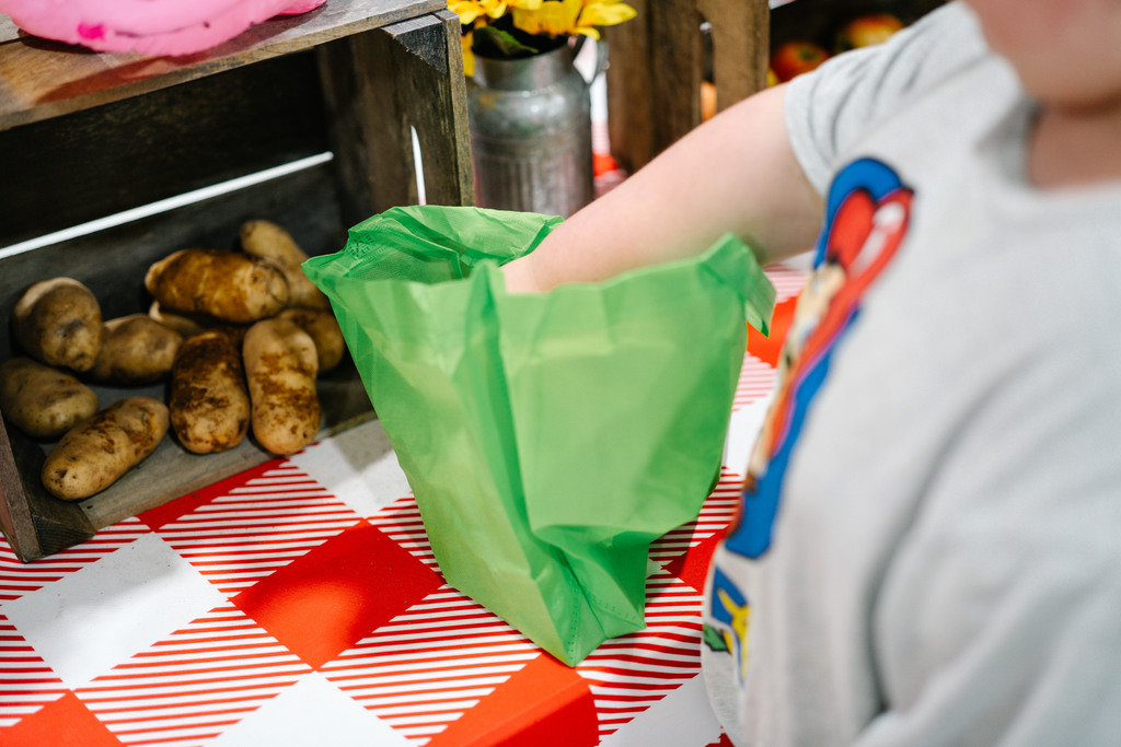 a malden student putting a wv grown potato in his farmers market bag.