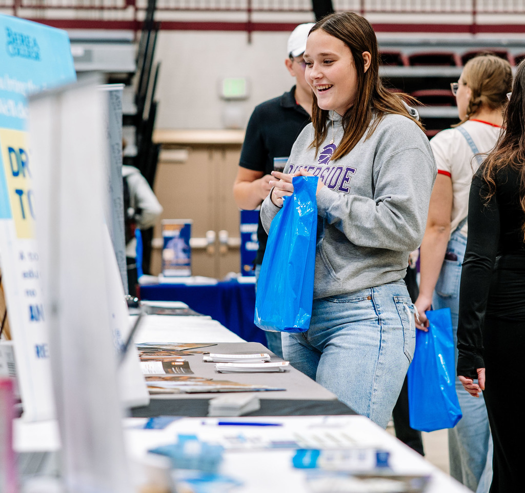 a student laughs with a university rep during the college fair. 