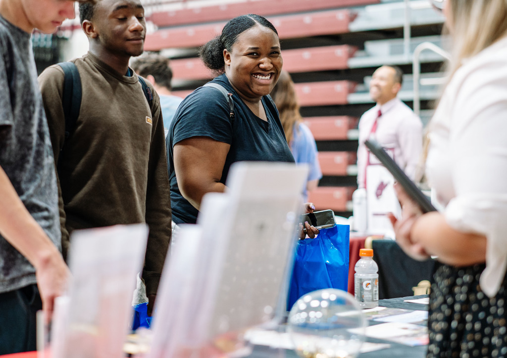 a high school student smiles at the camera while she talks with representatives from west virginia state university.