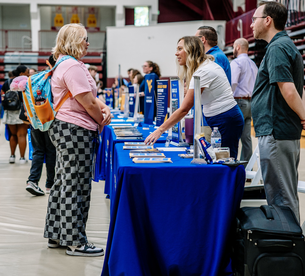 a student listening to a rep from west virginia university during the college fair.