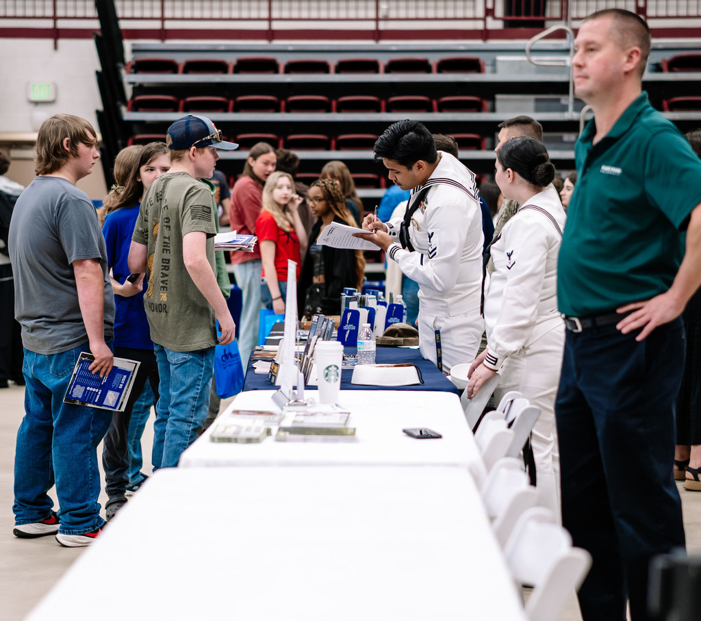 two representative from the united states navy speaking with high school students. 
