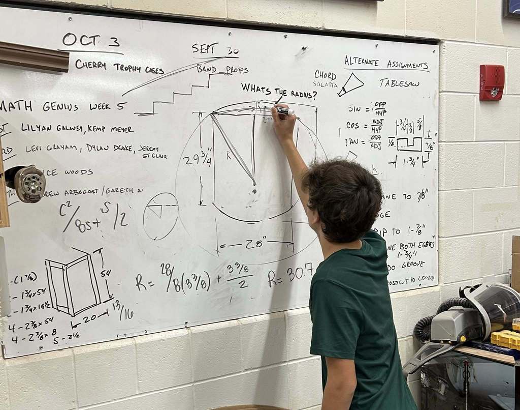 student writing on a white board solving a math problem.