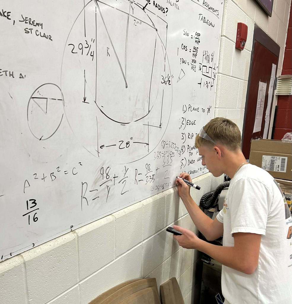 student writing on a white board solving a math problem.