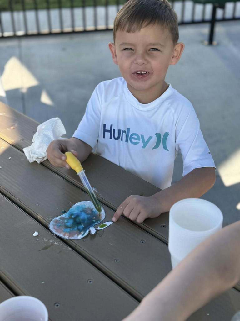 a student using a dropper filled with green liquid during a stem lesson in an outdoor classroom at cedar grove elementary