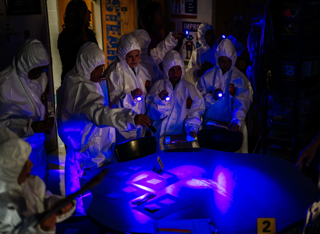 students using black lights to look for blood spatter.