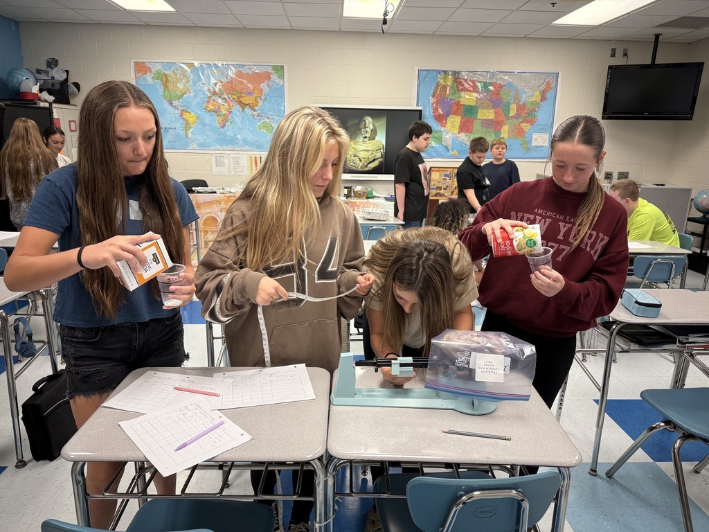 students at sissonville middle school using a scale to measure a chicken during their steam lab.