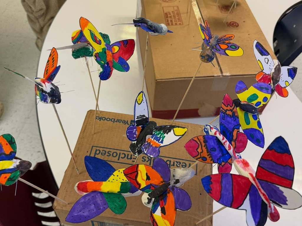 3D butterflies made by students attached to a box with a wooden dowels.