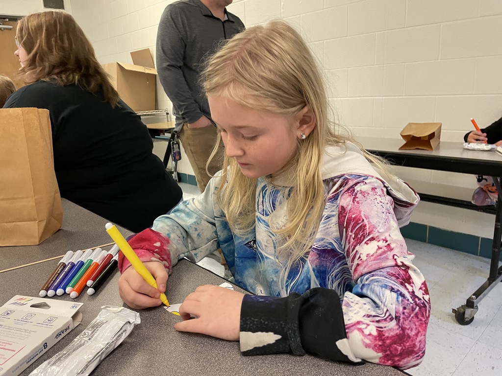 student using a yellow marker to color in a butterfly. 