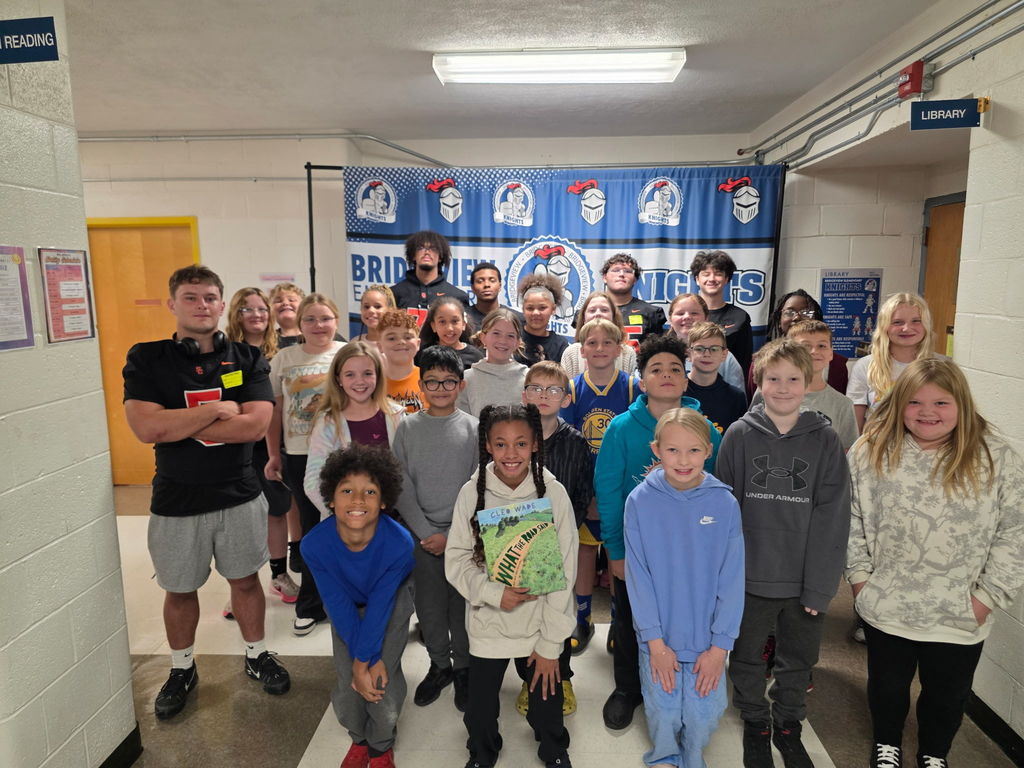 south charleston high school football players posing with a group of students from bridgeview elementary school. 