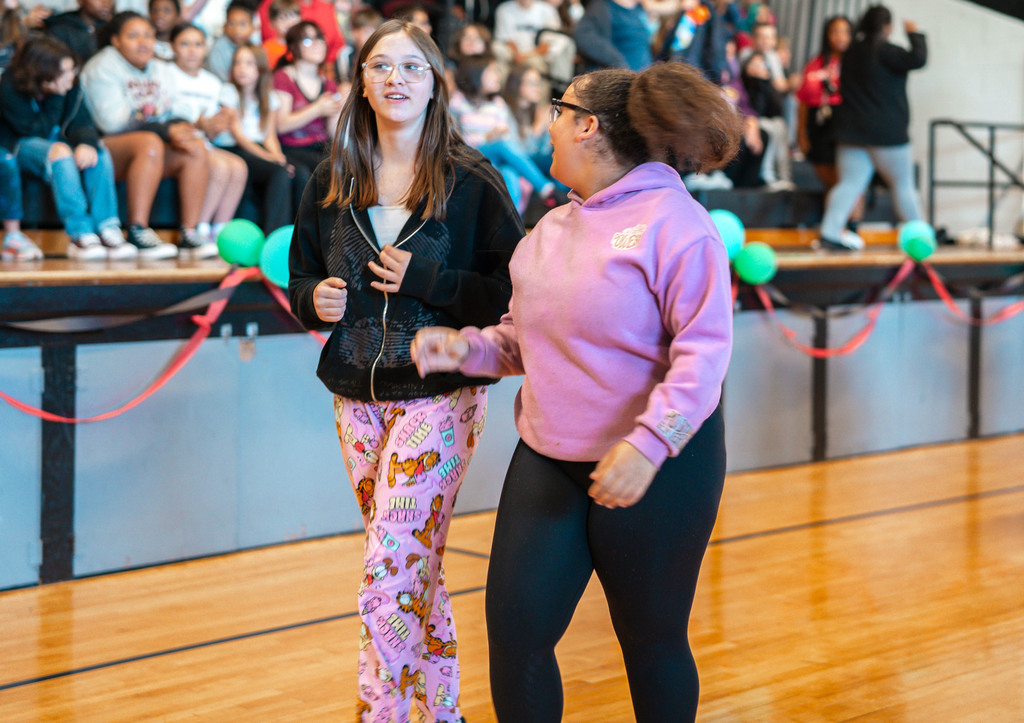 two students walking on the gym floor towards the inflatable sign.