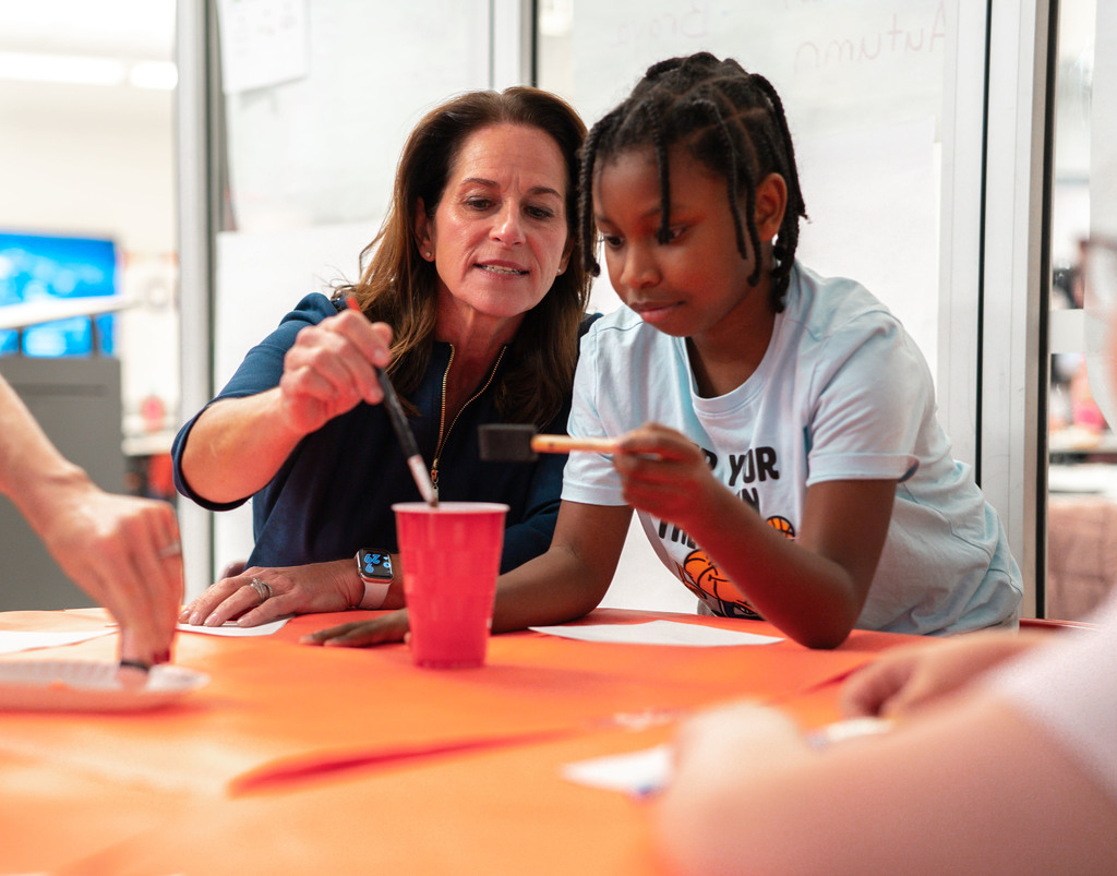 charleston mayor amy goodwin and an edgewood student washing off their brushes in a water cup.