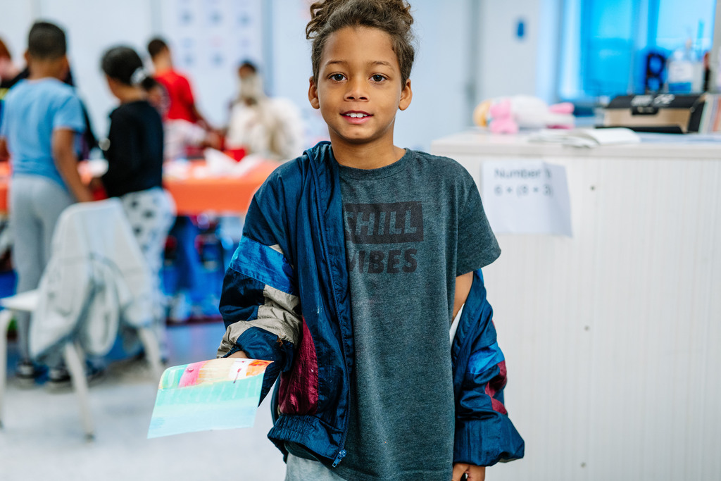 student showing off his art work while taking it to the drying rack.
