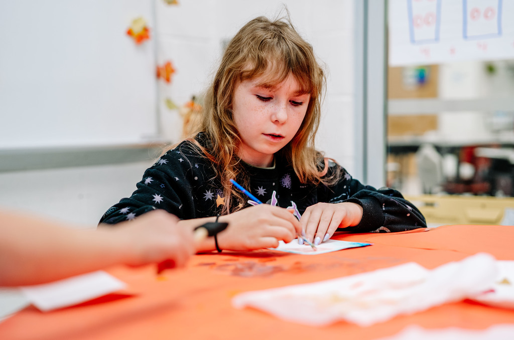 a girl painting on her paper with the color blue..