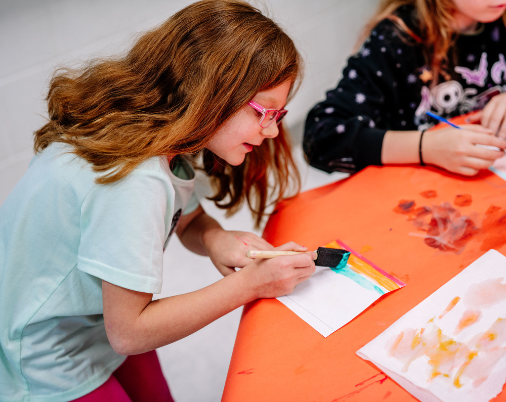 a student using the color teal to create a line in her art.