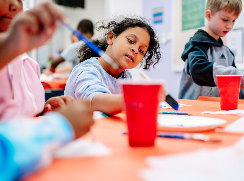 a student getting ready to dip her paint brush into a new color.