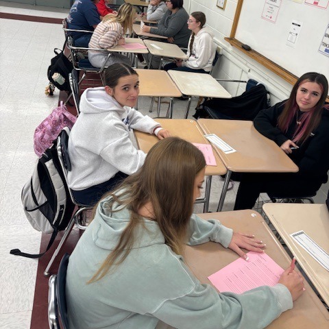 students sitting at their desks, filling out their worksheets, while solving geometry equations.