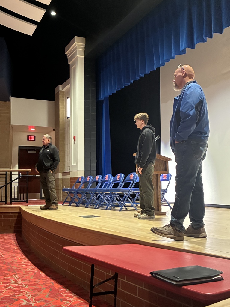 local contractor jerry hinzman, one of his employees, and herbert hoover high school's shop teacher on the stage in the school's auditorium talking with herbert hoover shop students.