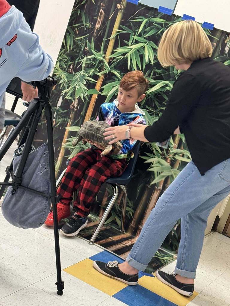 a cross lanes elementary teacher helping a student hold a turtle.