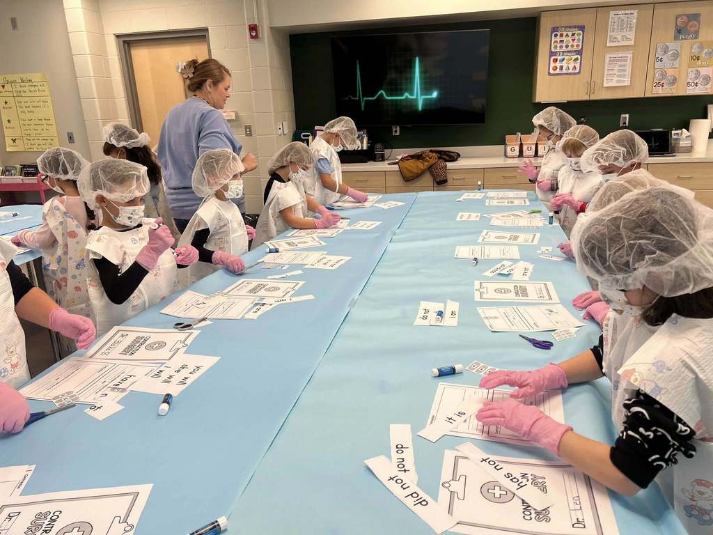 a table of students cutting and gluing words together during their contraction lesson.