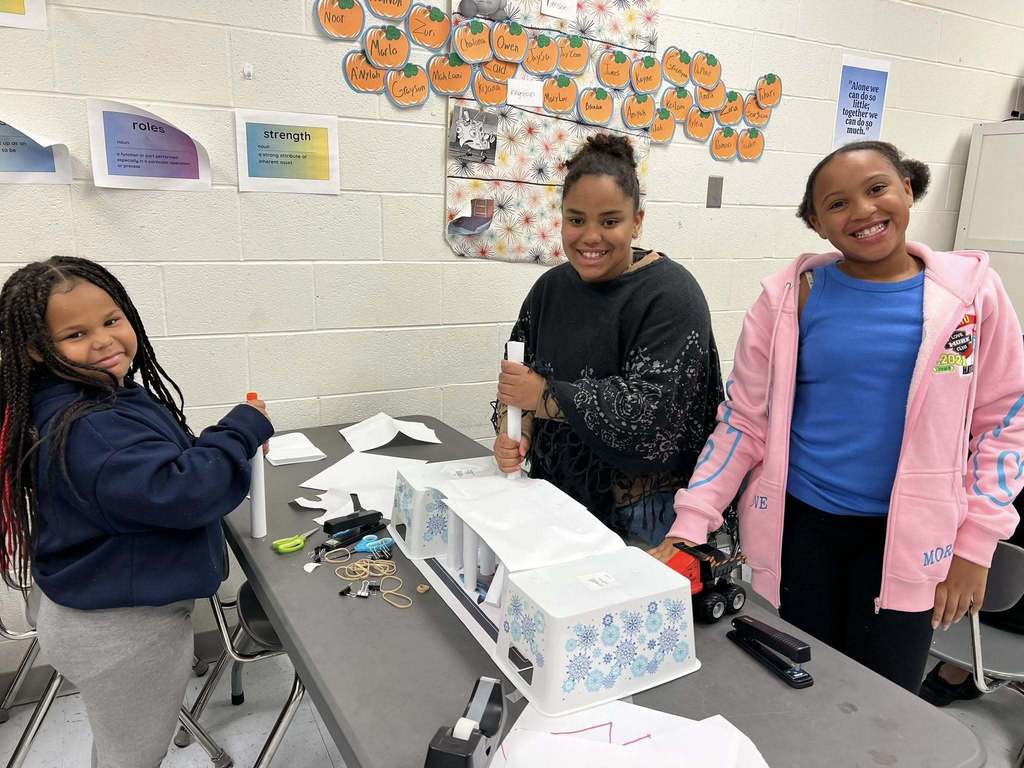 students smiling for a picture while building pillars for their bridge.