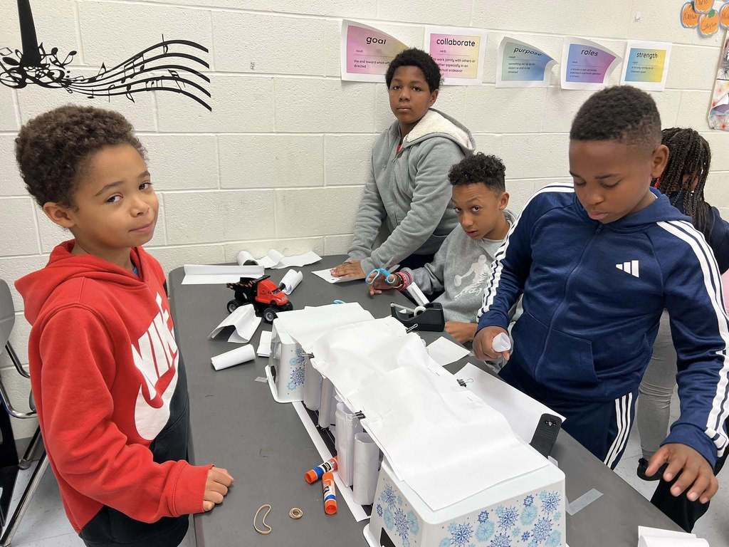 students taking a break from constructing their bridge to smile for a picture.