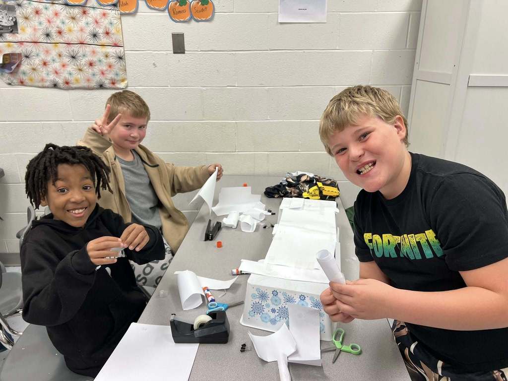 students smiling for a picture while they build their bridge.