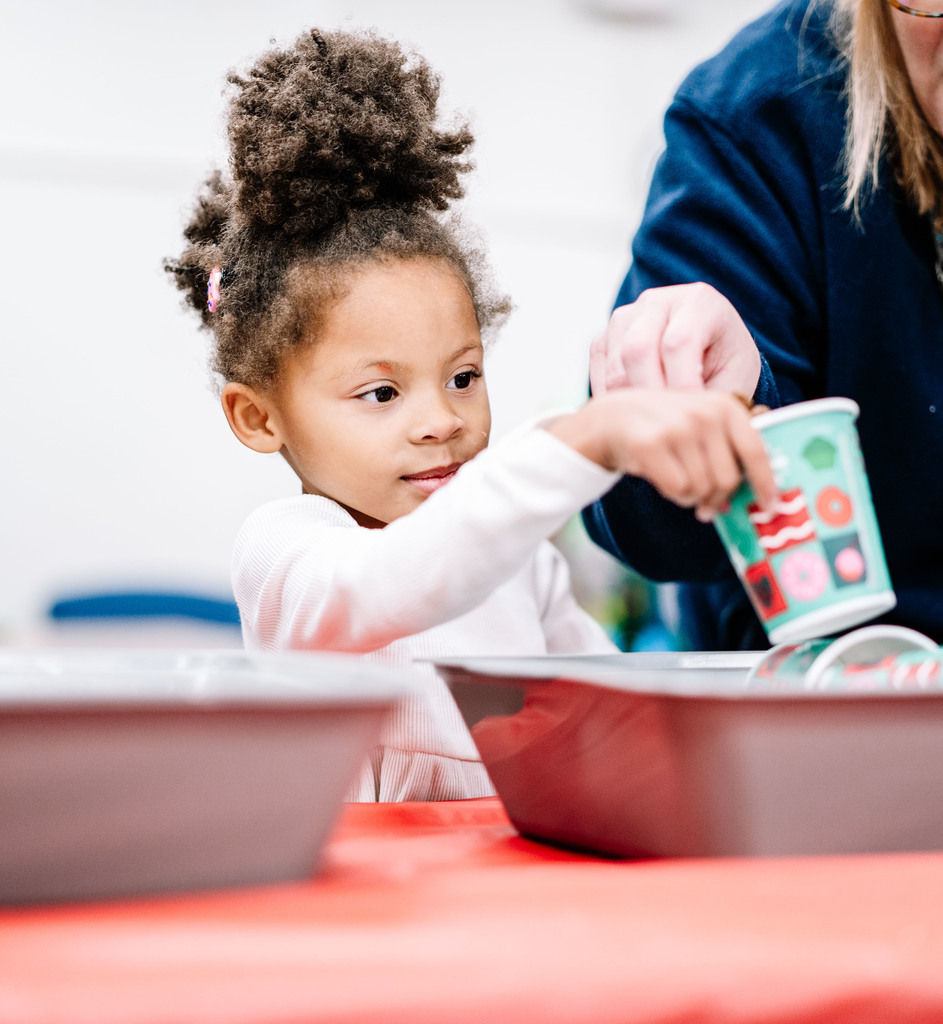 A student is standing in front of a bin holding a christmas themed cup.