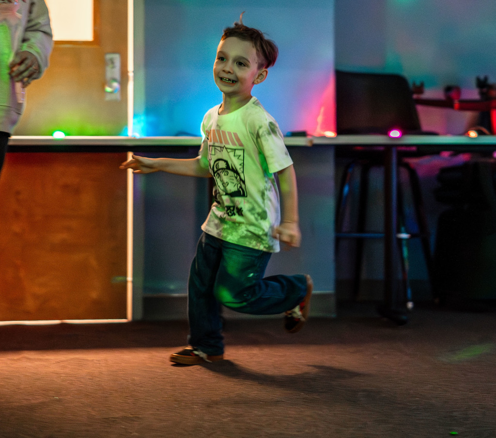 a student running around a room that has neon lights.
