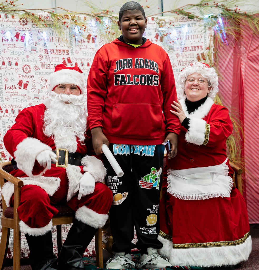 student standing in between santa and mrs. claus.