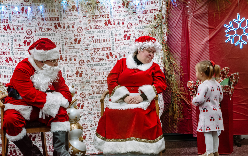 a young girl talking to santa and mrs. claus.