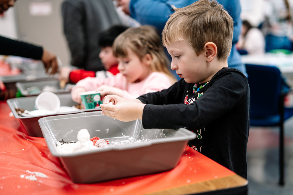students playing in sensory bins that are filled with different materials.