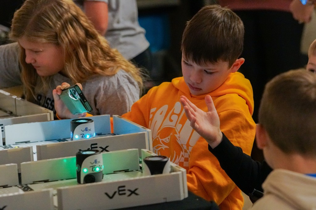a students is shining a light on his robot as he gets ready to put the robot into action.